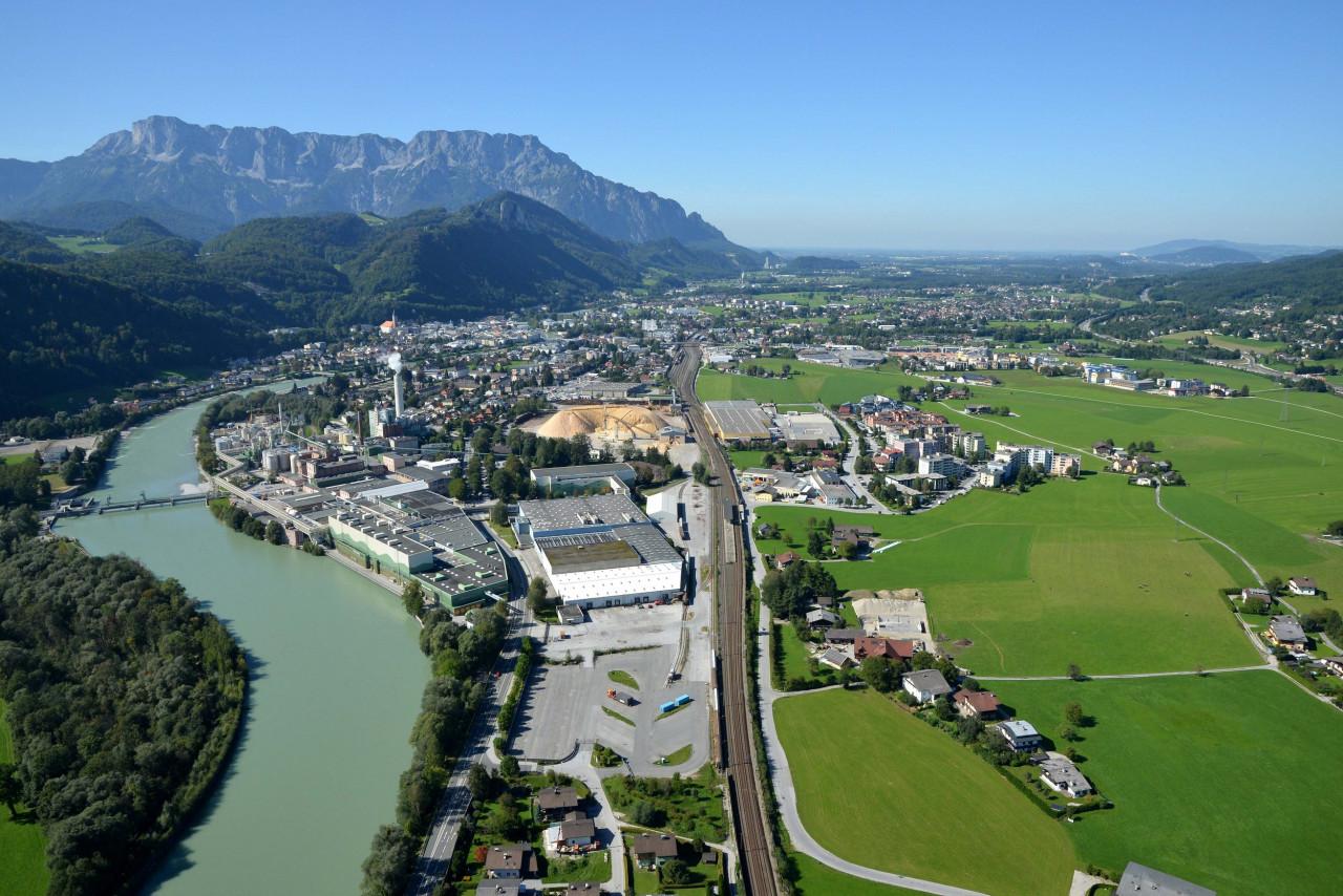 Aerial view of a manufacturing plant beside a river, railway and road in an Alpine valley